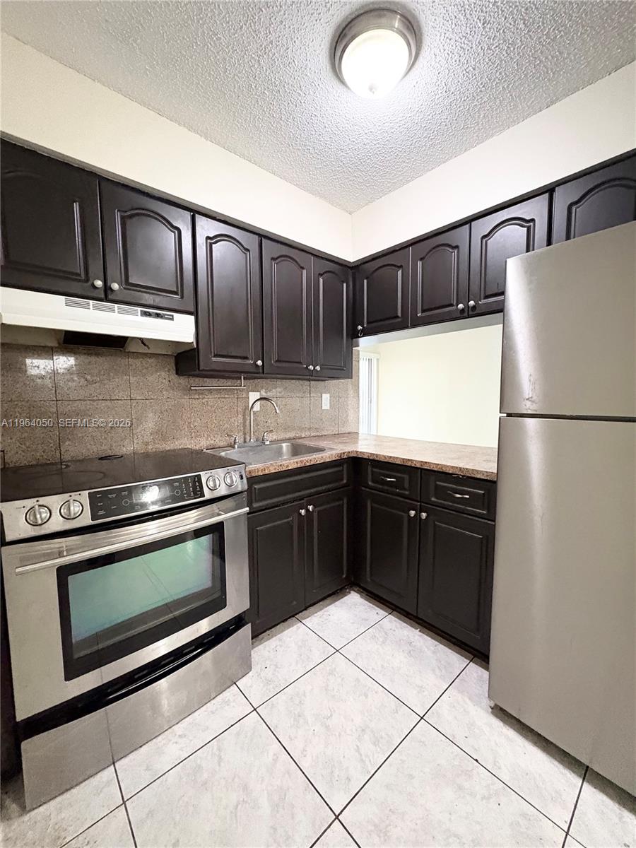 A kitchen features dark wood cabinets, stainless steel appliances, and a granite countertop — 813 SW 10th St # B, Hallandale Beach FL 33009, HALLANDALE BEACH, FL