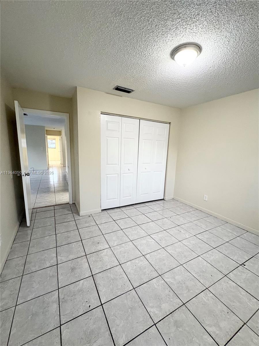 A room with white tile flooring, a white closet, and an open doorway to another room — 813 SW 10th St # B, Hallandale Beach FL 33009, HALLANDALE BEACH, FL