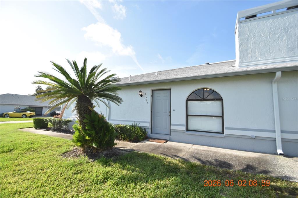 A single-story house exterior features a palm tree, a front door, and an arched window — 23223 CLUB VILLAS DRIVE UNIT 23223, LAND O LAKES, FL