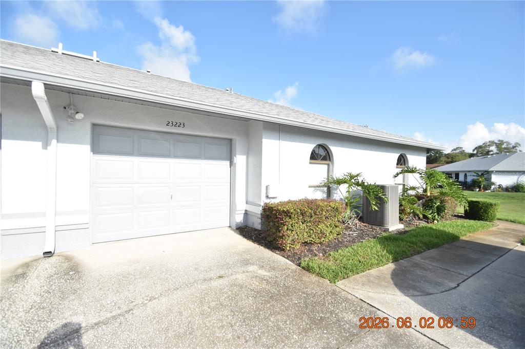 A white house exterior features a single-car garage, a concrete driveway, and arched windows — 23223 CLUB VILLAS DRIVE UNIT 23223, LAND O LAKES, FL