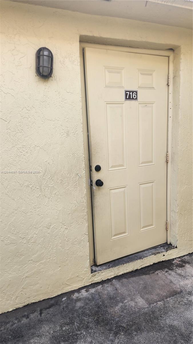 A beige exterior door with the number 716 is set into a textured stucco wall — 1045 S Flagler Ave # 716, Pompano Beach FL 33060, POMPANO BEACH, FL