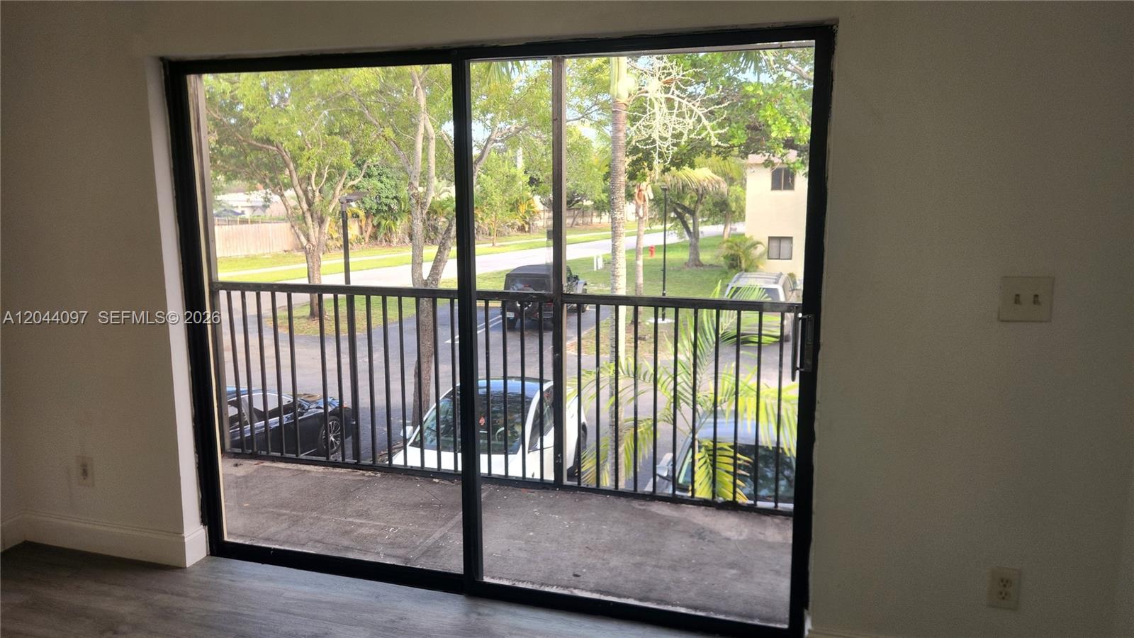 A sliding glass door opens onto a balcony overlooking a parking lot and trees — 1045 S Flagler Ave # 716, Pompano Beach FL 33060, POMPANO BEACH, FL