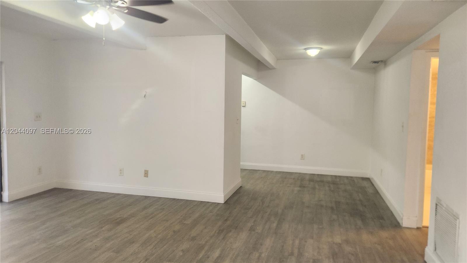 An empty room features white walls, gray wood-look flooring, and a ceiling fan — 1045 S Flagler Ave # 716, Pompano Beach FL 33060, POMPANO BEACH, FL