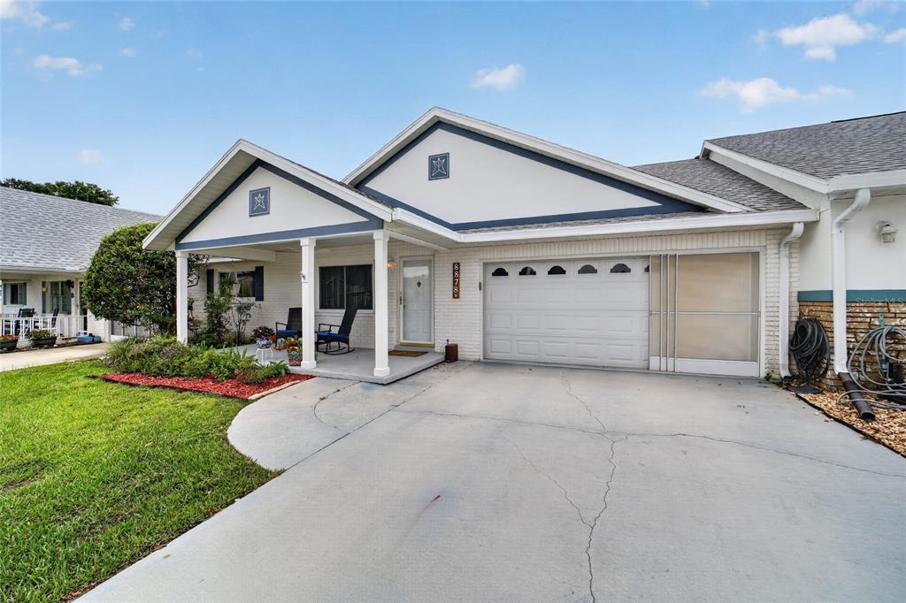 A single-story house features a white brick exterior, a covered front porch, and a garage — 8878 SW 90TH LANE N UNIT B, OCALA, FL