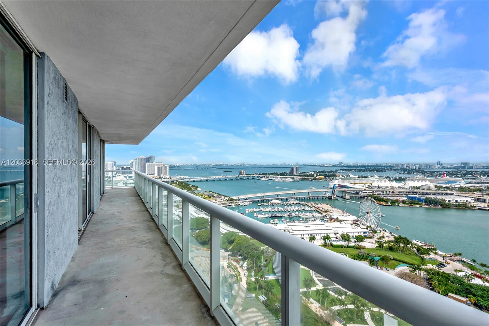 A high-rise balcony overlooks a marina, a Ferris wheel, and a bridge over the water — 50 Biscayne Blvd # 3802, Miami FL 33132, MIAMI, FL