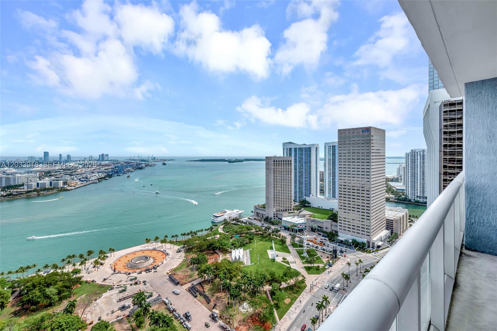 A high-angle view from a balcony overlooking a waterfront park and city skyline — 50 Biscayne Blvd # 3802, Miami FL 33132, MIAMI, FL