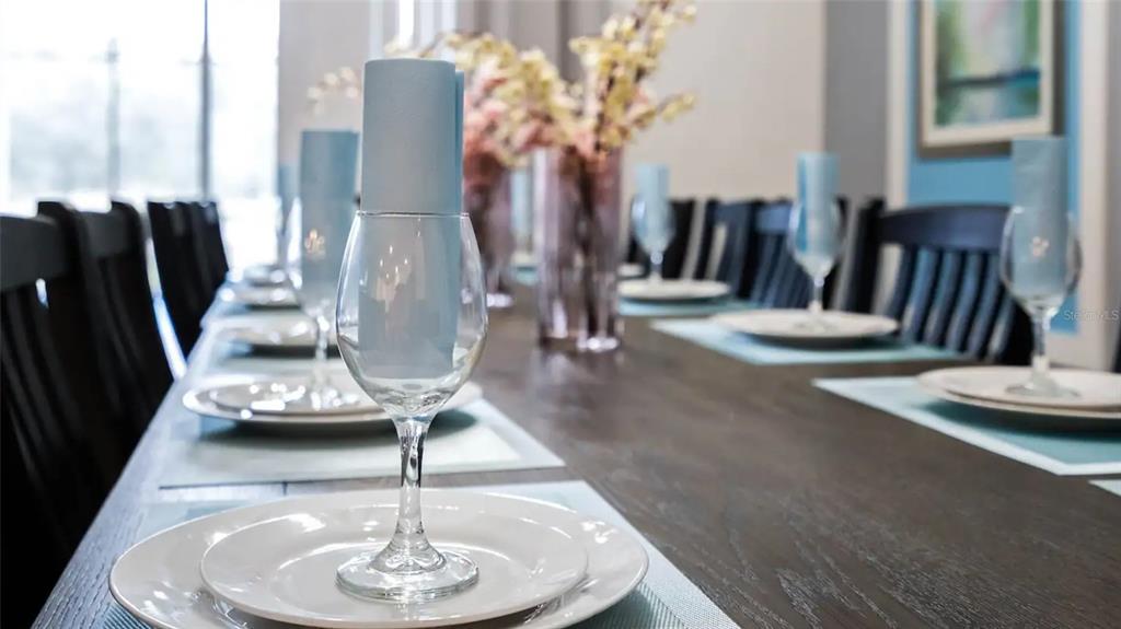 A dining room table is set with plates, wine glasses, and light blue napkins — 2965 PROTAGONIST STREET, KISSIMMEE, FL