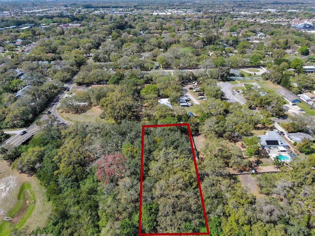 An aerial view shows a rectangular, tree-covered vacant lot outlined in red — 1971 WOLFORD ROAD, CLEARWATER, FL