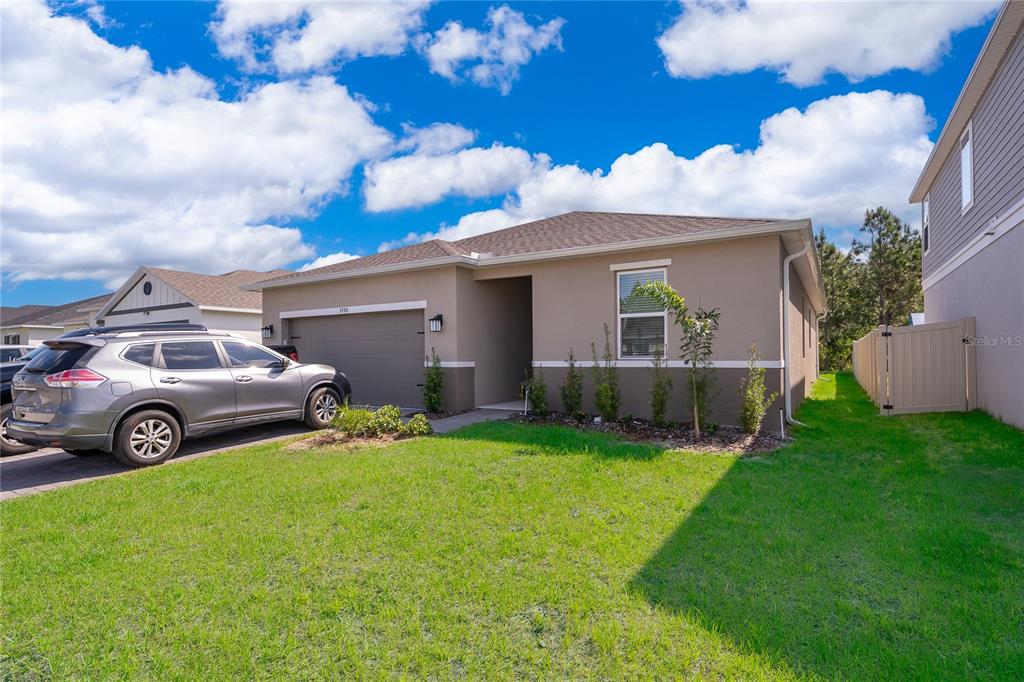 A single-story house with a tan exterior, a two-car garage, and a parked SUV — 3390 SANCTUARY DRIVE, CLERMONT, FL
