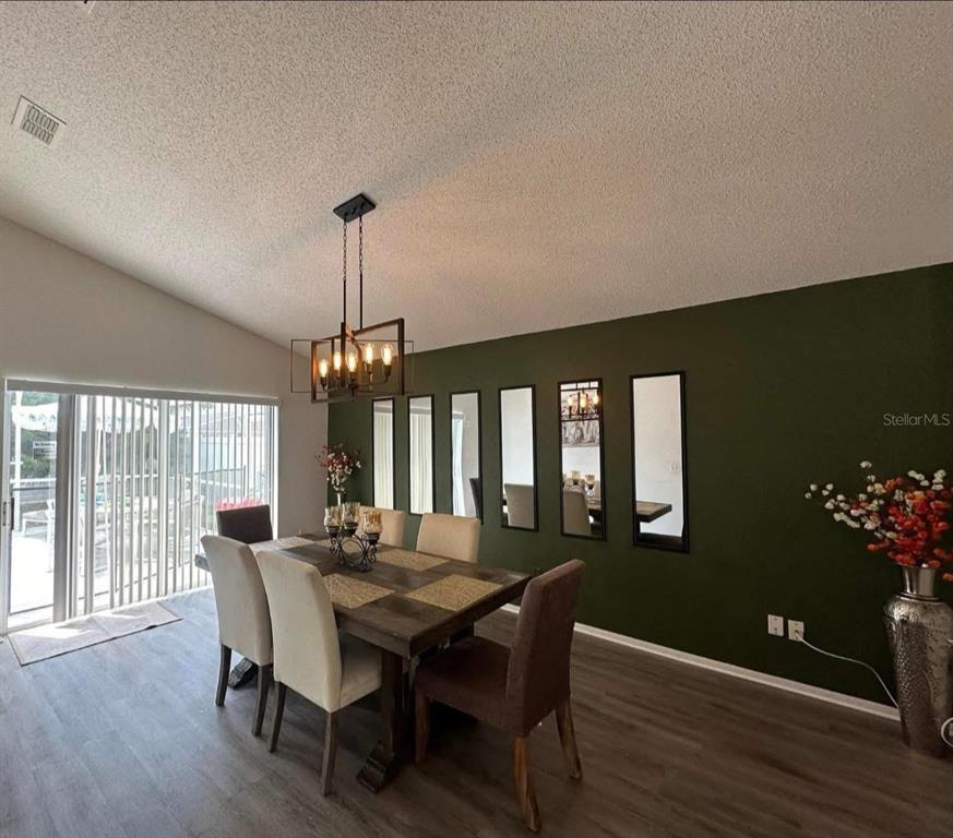 A dining room features a dark wood table, upholstered chairs, and mirrors on a green wall — 121 BLOOMINGDALE DRIVE, DAVENPORT, FL