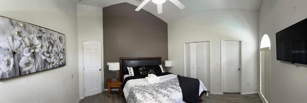 A bedroom features a vaulted ceiling, a bed with a patterned comforter, and wall art — 121 BLOOMINGDALE DRIVE, DAVENPORT, FL