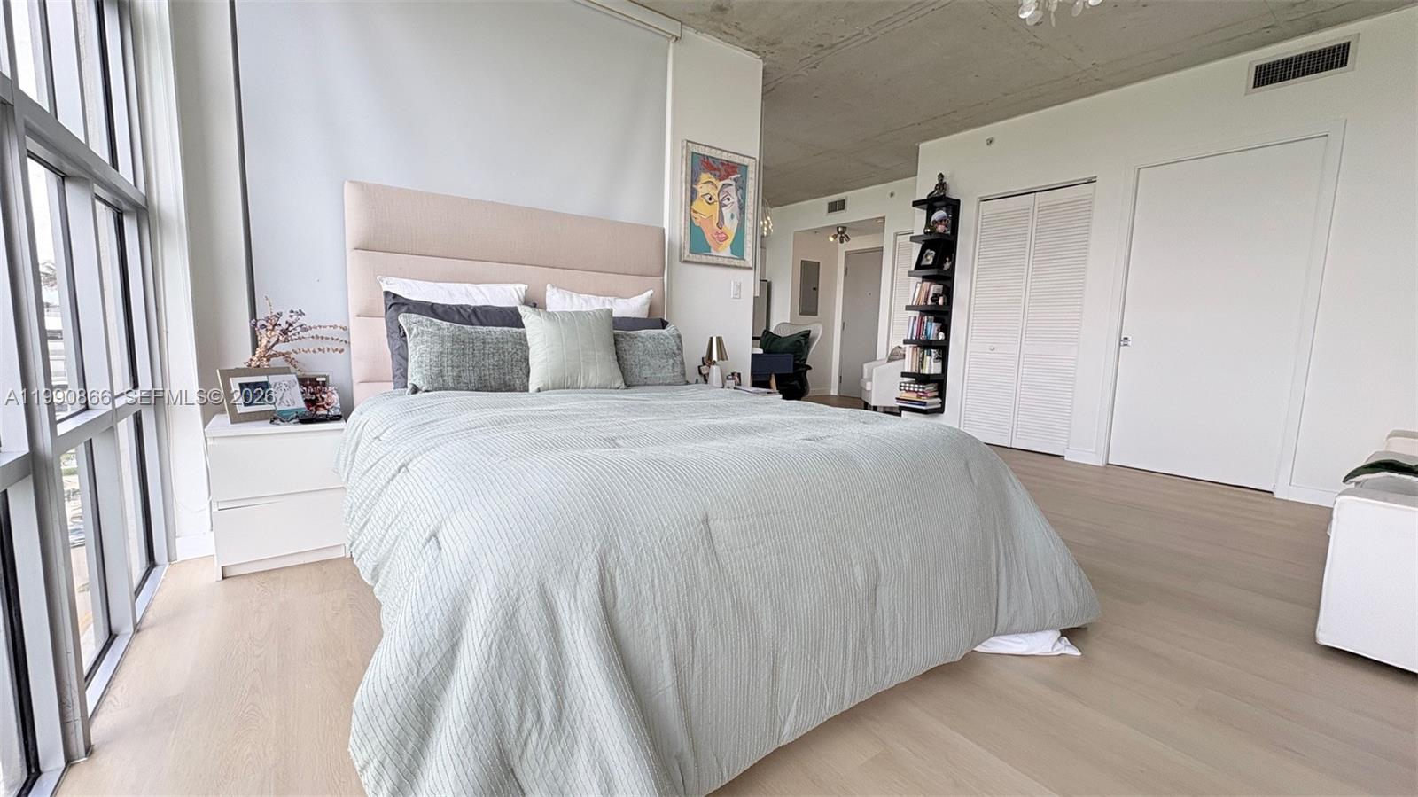 A bedroom features a light-colored bed, wood flooring, a concrete ceiling, and floor-to-ceiling windows — 3451 NE 1st Ave # M0703, Miami FL 33137, MIAMI, FL