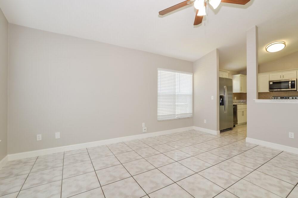 A dining area with light gray walls, tile flooring, and an open view into the kitchen — 9599 LUPINE AVENUE, ORLANDO, FL