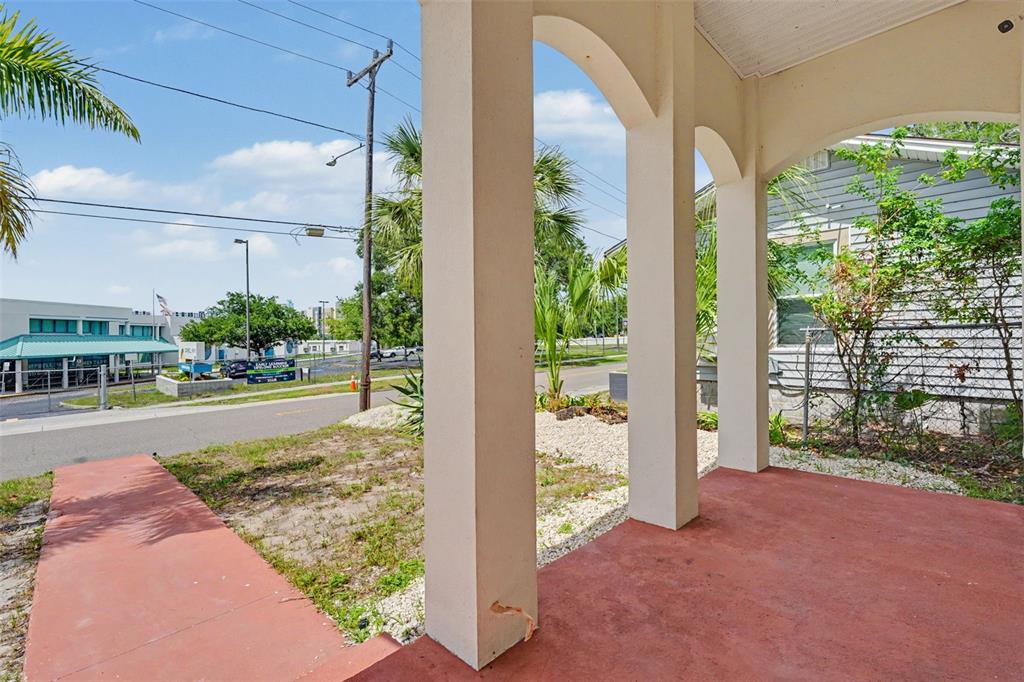 A covered porch with arched columns overlooks a street and a nearby commercial building — 1018 7TH AVENUE S, ST PETERSBURG, FL