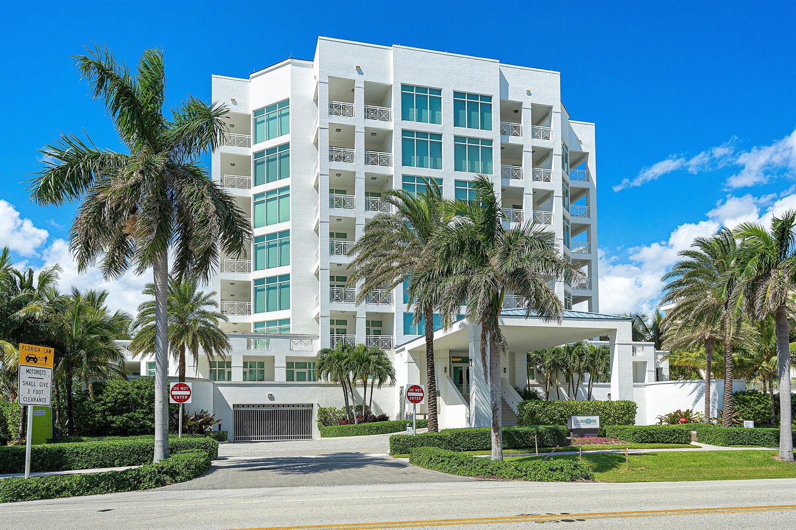 A multi-story white residential building with balconies, large windows, and palm trees in the foreground — 3200 S Ocean Boulevard # 201, Highland Beach FL 33487, HIGHLAND BEACH, FL