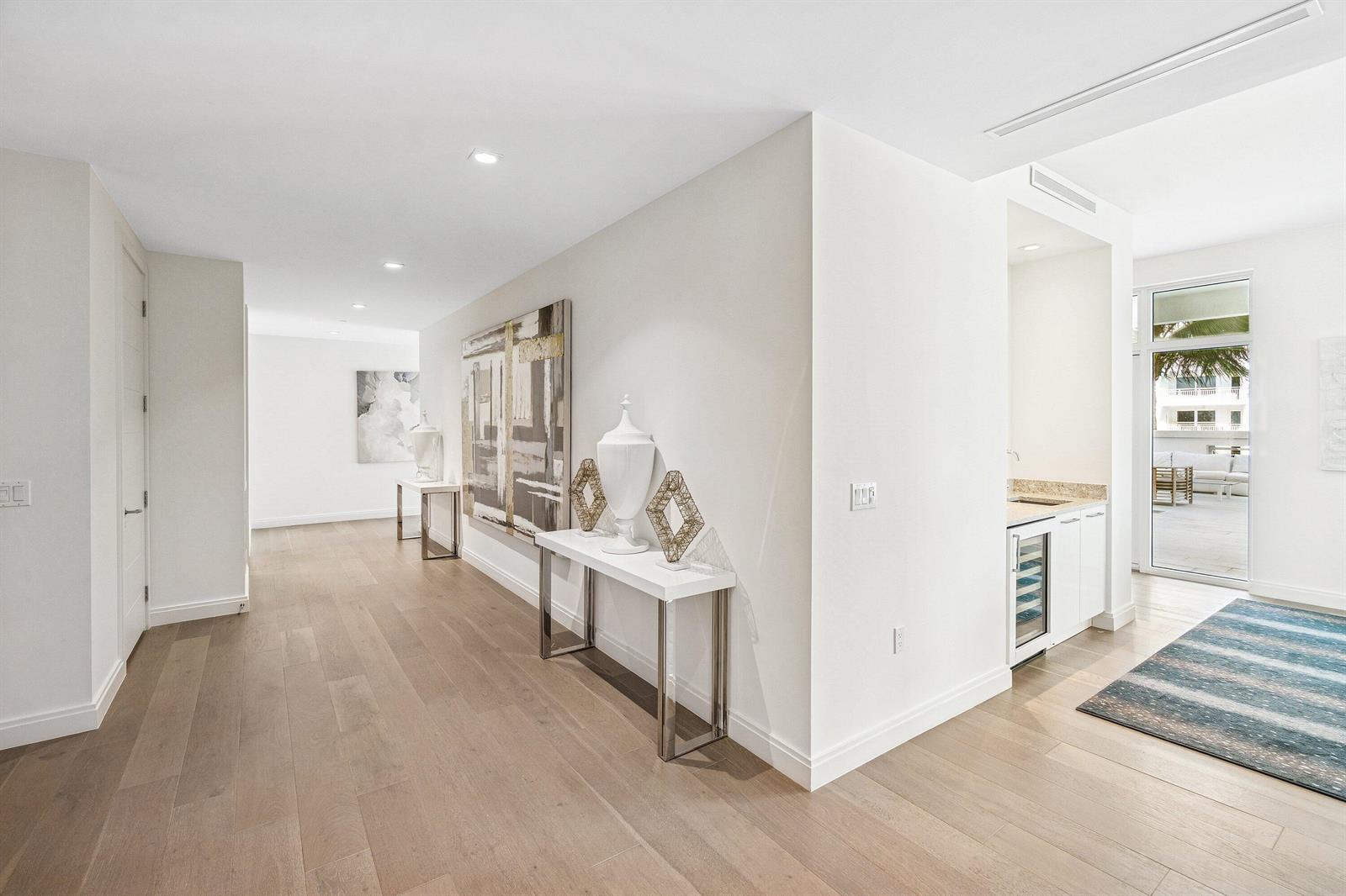 A bright hallway features light wood floors, a console table, artwork, and a wet bar — 3200 S Ocean Boulevard # 201, Highland Beach FL 33487, HIGHLAND BEACH, FL