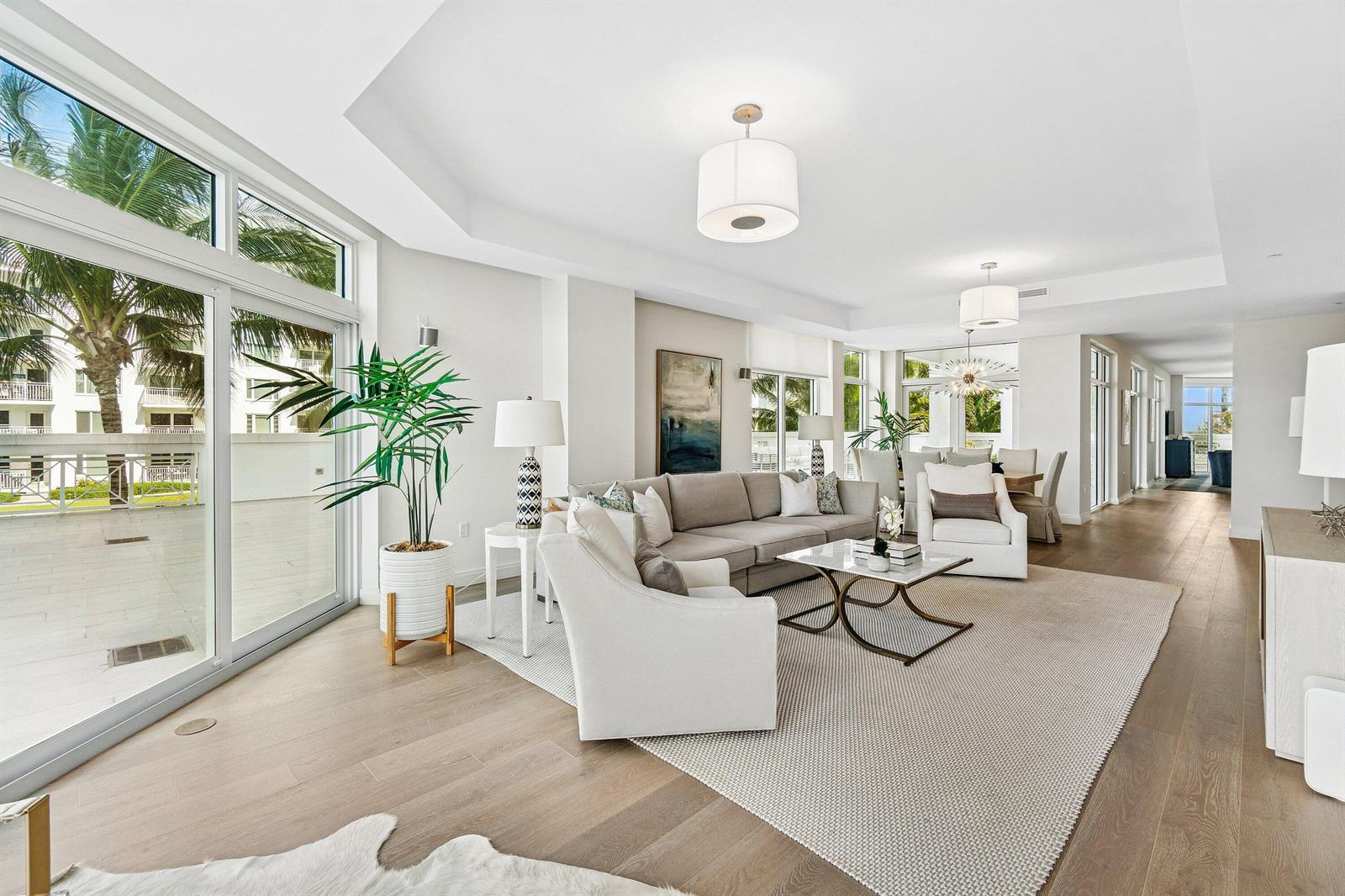 A bright living room features light wood floors, a neutral sofa, and large sliding glass doors — 3200 S Ocean Boulevard # 201, Highland Beach FL 33487, HIGHLAND BEACH, FL