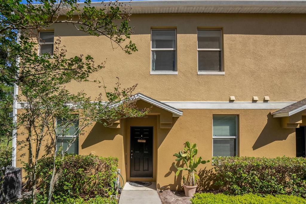 A two-story tan stucco townhouse exterior features a black front door and a small walkway — 2144 BETSY ROSS LANE, ST CLOUD, FL