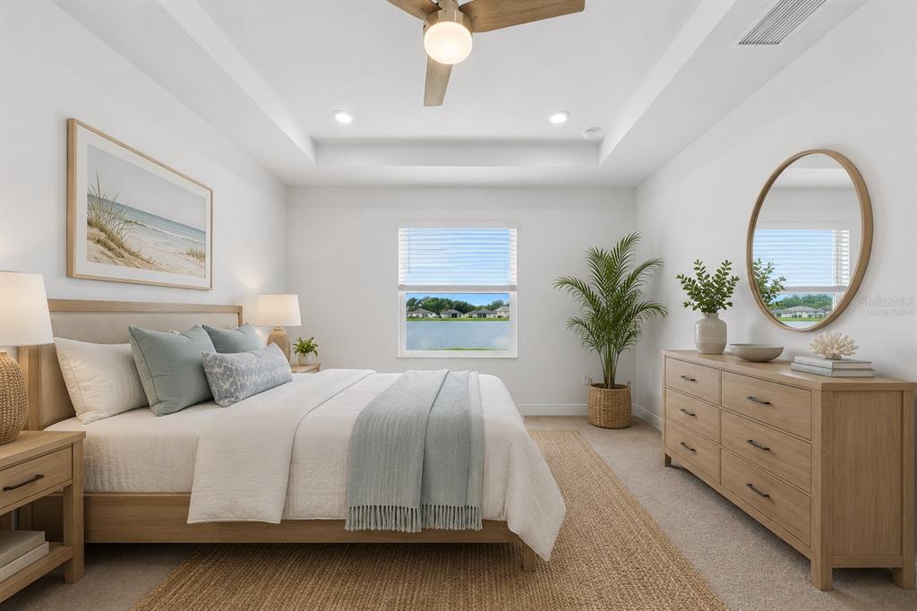 A bedroom features a wooden bed frame, a dresser with a mirror, and a lake view — 9959 LAST LIGHT GLEN, PARRISH, FL