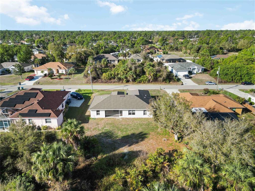 An aerial view shows three suburban houses with backyards and surrounding trees — 1698 N LAVINA STREET, NORTH PORT, FL