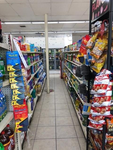 A narrow aisle in a convenience store features shelves stocked with various household and food products — 5600 NE 2nd Ave # A, Miami FL 33137, MIAMI, FL