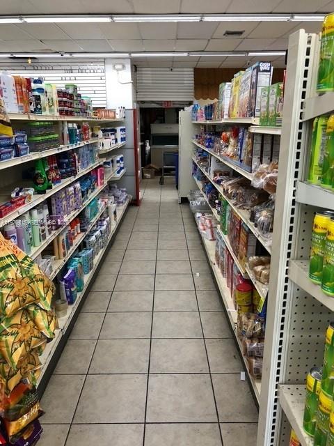 A narrow aisle in a convenience store features metal shelving stocked with various food products — 5600 NE 2nd Ave # A, Miami FL 33137, MIAMI, FL