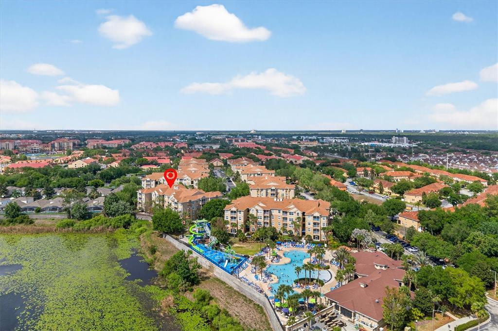 An aerial view of a multi-story apartment complex with a pool and water slide — 7664 COMROW STREET UNIT 304, KISSIMMEE, FL