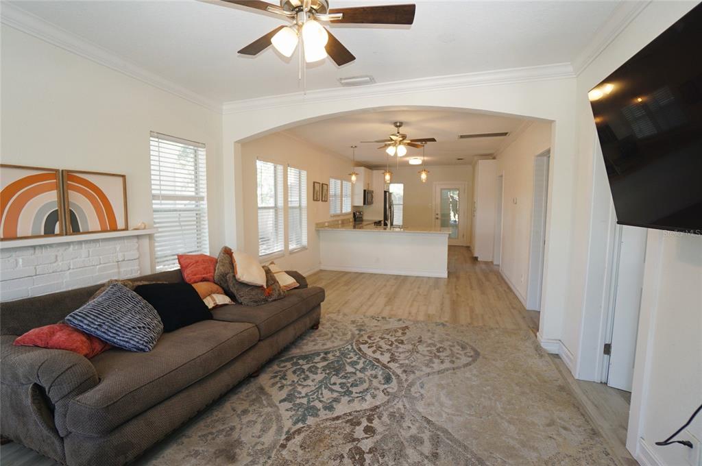 A living room with a sofa and rug opens into a kitchen with white cabinetry — 2511 W FIG STREET, TAMPA, FL