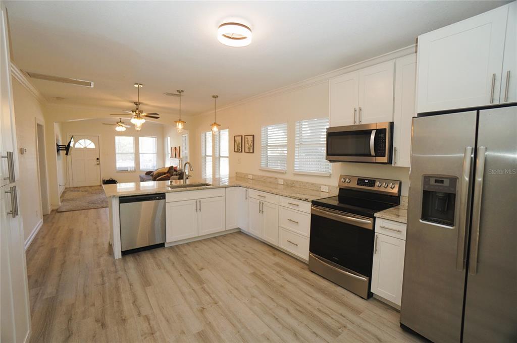 A kitchen with white cabinets, stainless steel appliances, and light wood-look flooring — 2511 W FIG STREET, TAMPA, FL