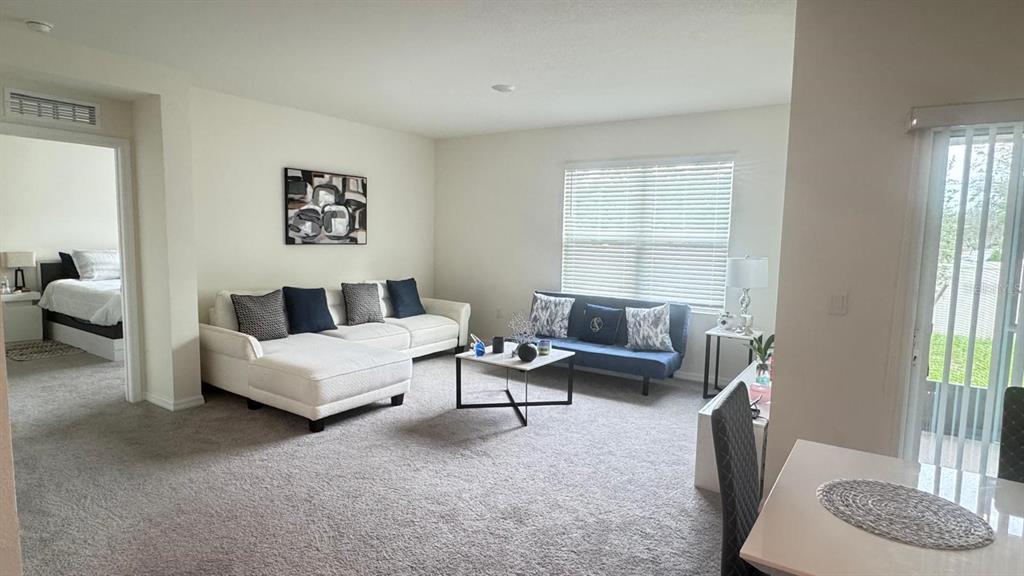 A living room features a white sectional sofa, a blue futon, and a coffee table — 2175 DOE RUN DRIVE, DAVENPORT, FL