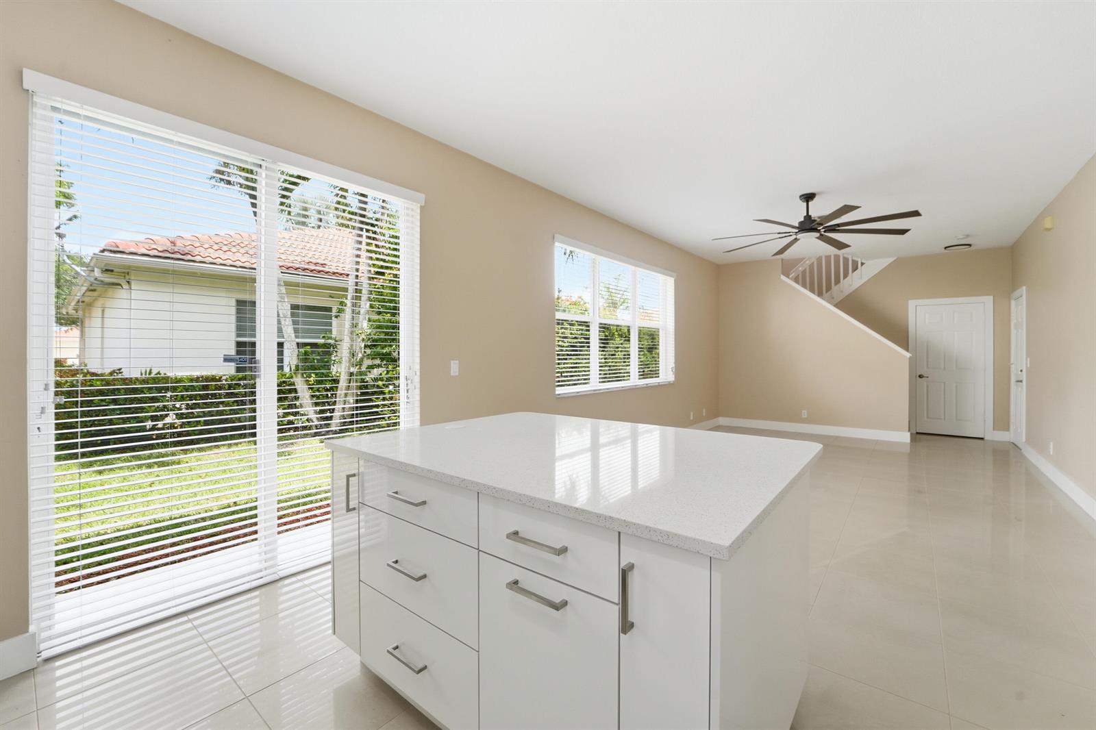 A kitchen island with white cabinets and a quartz countertop sits in a bright room — 1780 Pierside Circle, Wellington FL 33414, WELLINGTON, FL