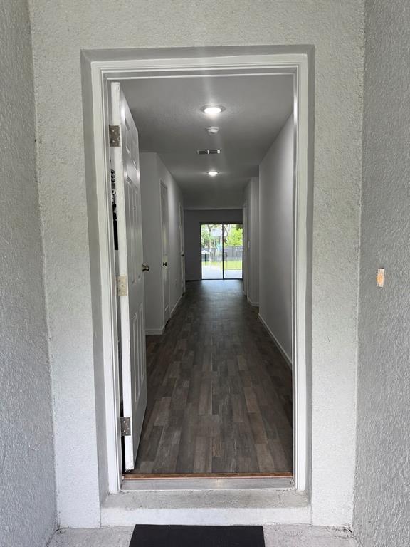 A view through an open doorway into a hallway with wood-look flooring and recessed lighting — 12150 FOLGER STREET, SPRING HILL, FL