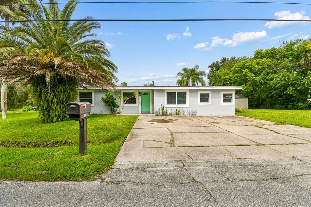 A single-story house with a light gray exterior, a teal front door, and a concrete driveway — 173 TEMPLE STREET, NEW SMYRNA BEACH, FL