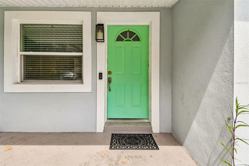 A light green front door with a window sits next to a window on a porch — 173 TEMPLE STREET, NEW SMYRNA BEACH, FL