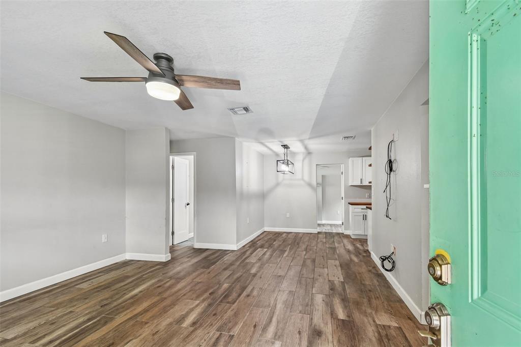An interior view of a living area with wood-look flooring, a ceiling fan, and light-colored walls — 173 TEMPLE STREET, NEW SMYRNA BEACH, FL