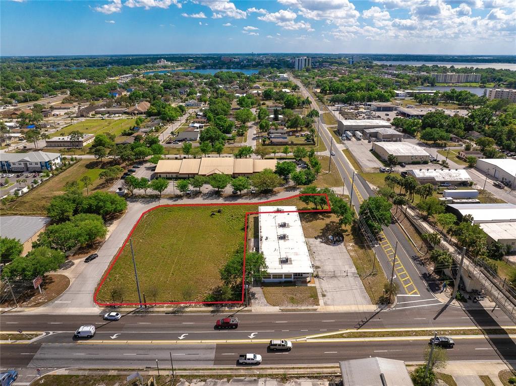 An aerial view shows a vacant lot and an adjacent commercial building next to a road — 0 OLYMPIAN WAY, WINTER HAVEN, FL