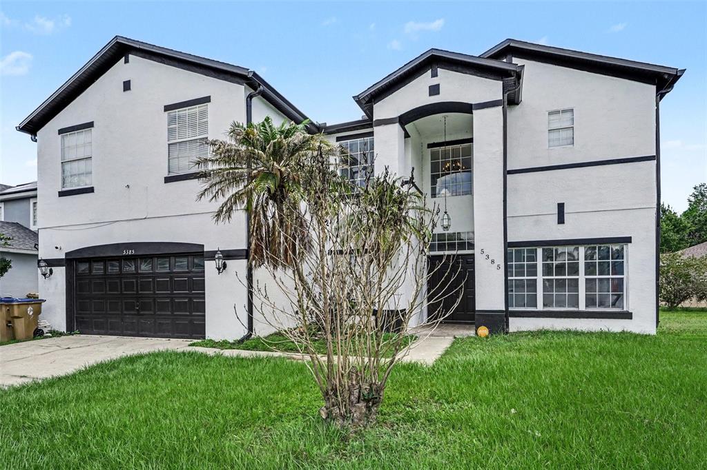 A two-story house with white stucco walls, black trim, a garage, and a front lawn — 5385 DAHLIA RESERVE DRIVE, KISSIMMEE, FL