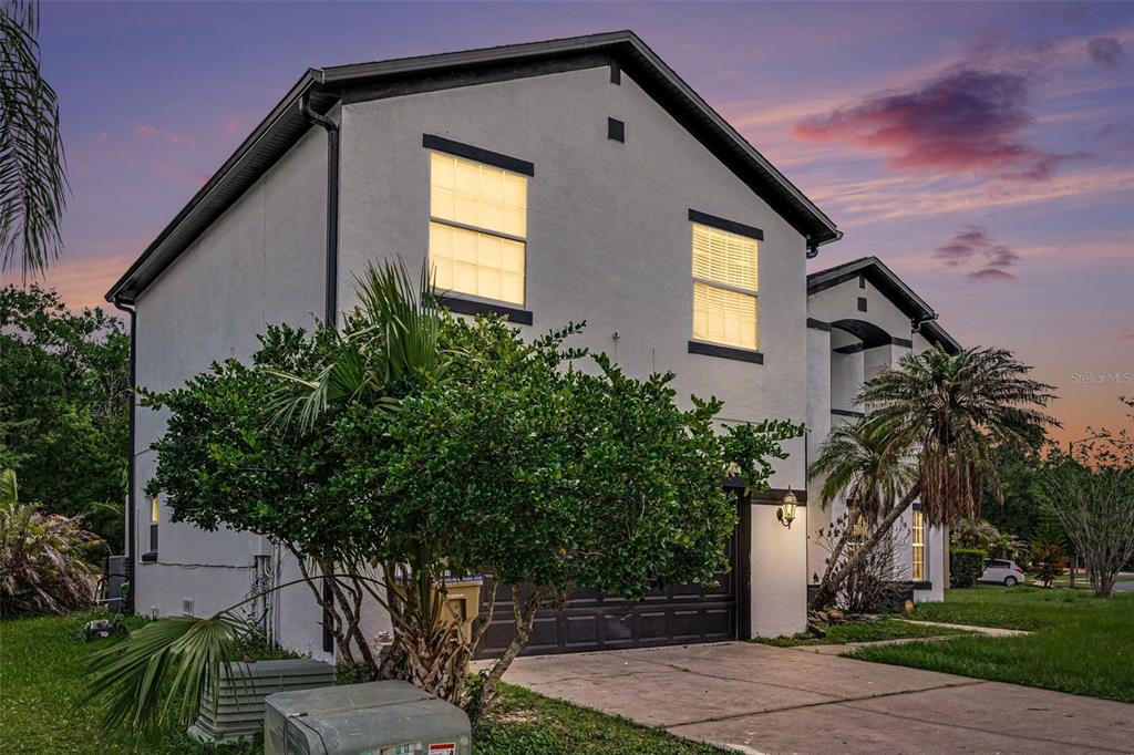 A two-story house with a concrete driveway, a garage, and a large tree in front — 5385 DAHLIA RESERVE DRIVE, KISSIMMEE, FL