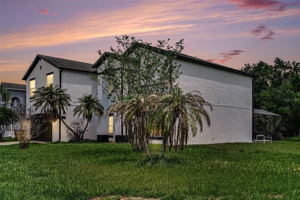 A two-story white stucco house with a dark roof, palm trees, and a screened-in patio — 5385 DAHLIA RESERVE DRIVE, KISSIMMEE, FL