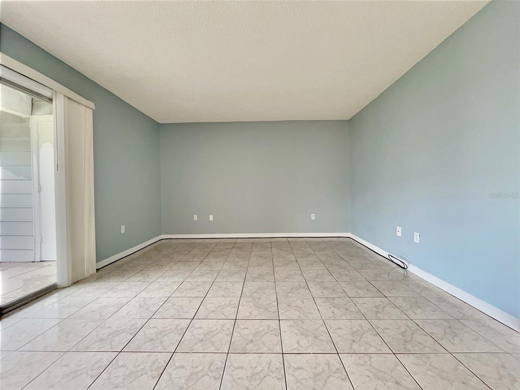 An empty room with light blue walls, tile flooring, and a sliding glass door — 865 SKY LAKE CIRCLE UNIT D, ORLANDO, FL