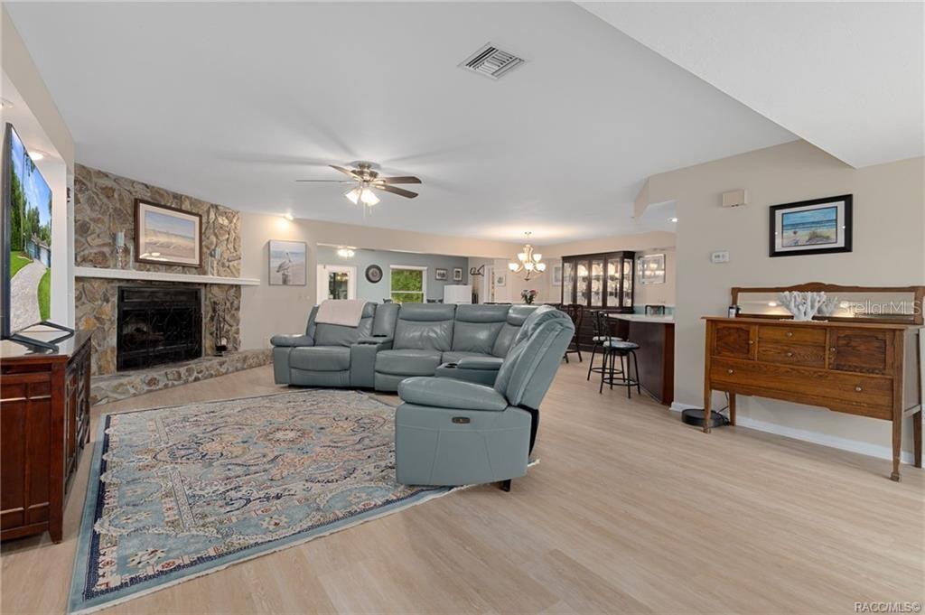 A living room features a stone fireplace, a blue sectional sofa, and light wood flooring — 11678 W TIMBERLANE DRIVE, HOMOSASSA, FL