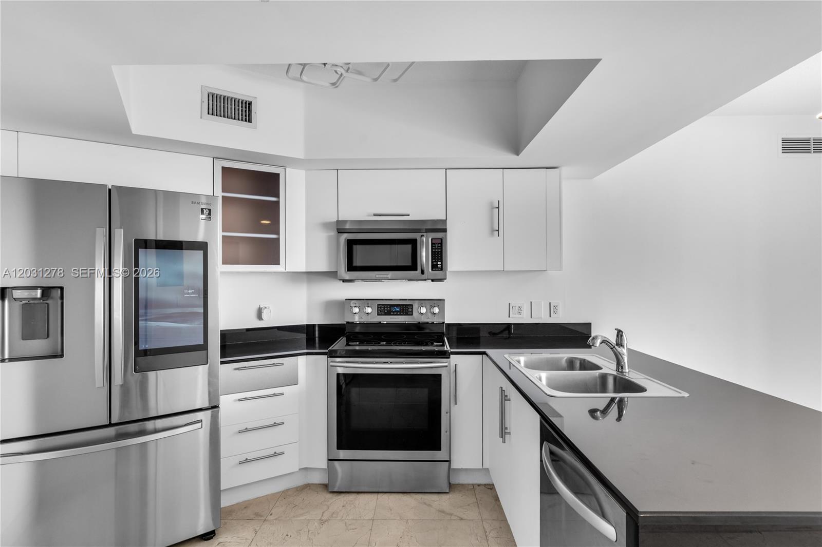 A modern kitchen features white cabinets, stainless steel appliances, and black countertops — 1750 N Bayshore Dr # 4414, Miami FL 33132, MIAMI, FL