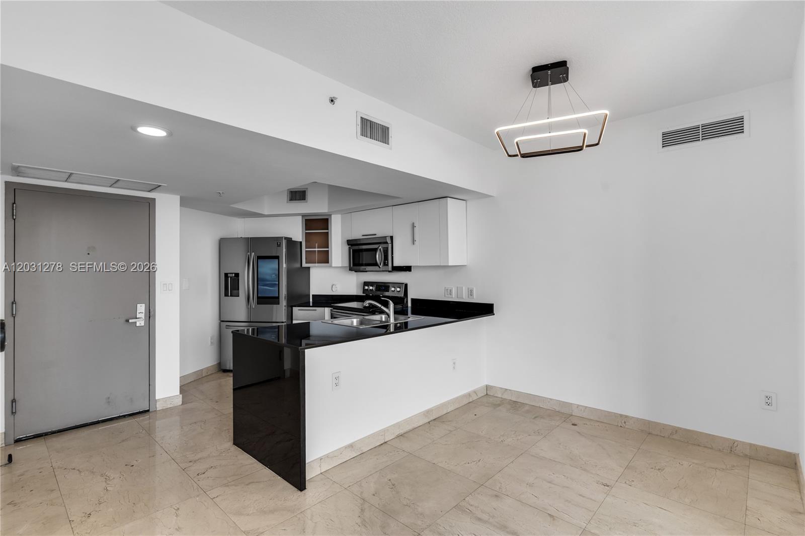 A kitchen with black countertops, white cabinets, and stainless steel appliances sits on tiled floors — 1750 N Bayshore Dr # 4414, Miami FL 33132, MIAMI, FL