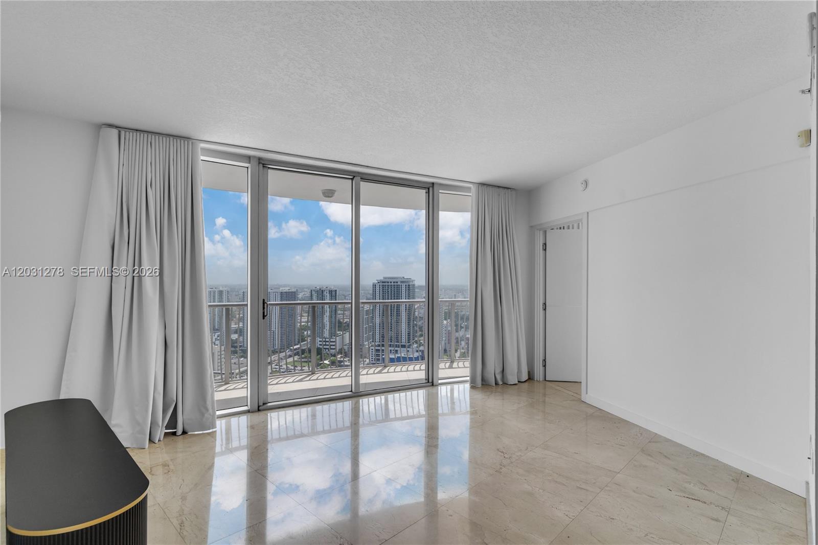 An empty room with marble floors, floor-to-ceiling windows, and a view of city skyscrapers — 1750 N Bayshore Dr # 4414, Miami FL 33132, MIAMI, FL