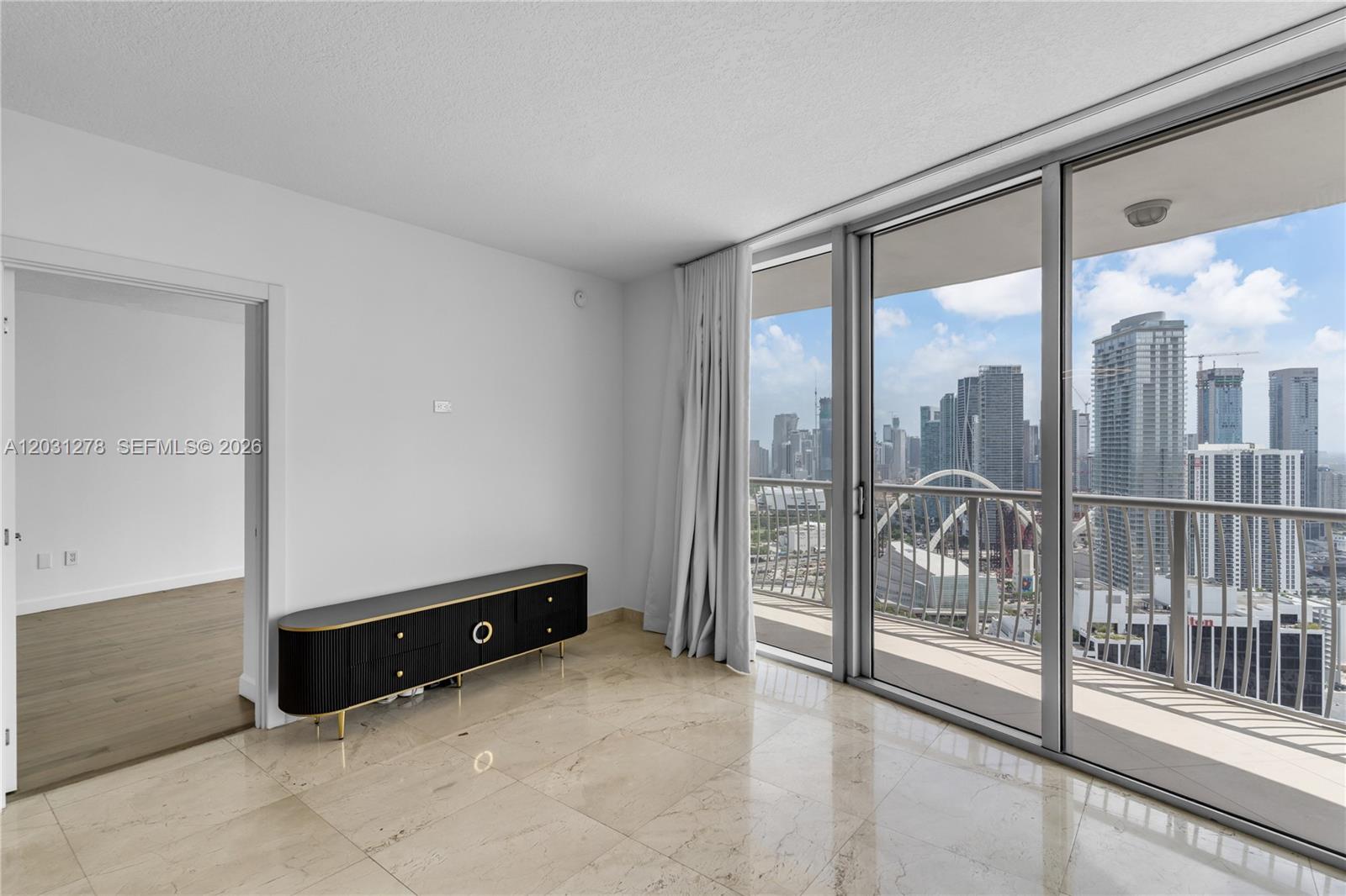 A living room with marble floors, a black media console, and a balcony overlooking skyscrapers — 1750 N Bayshore Dr # 4414, Miami FL 33132, MIAMI, FL