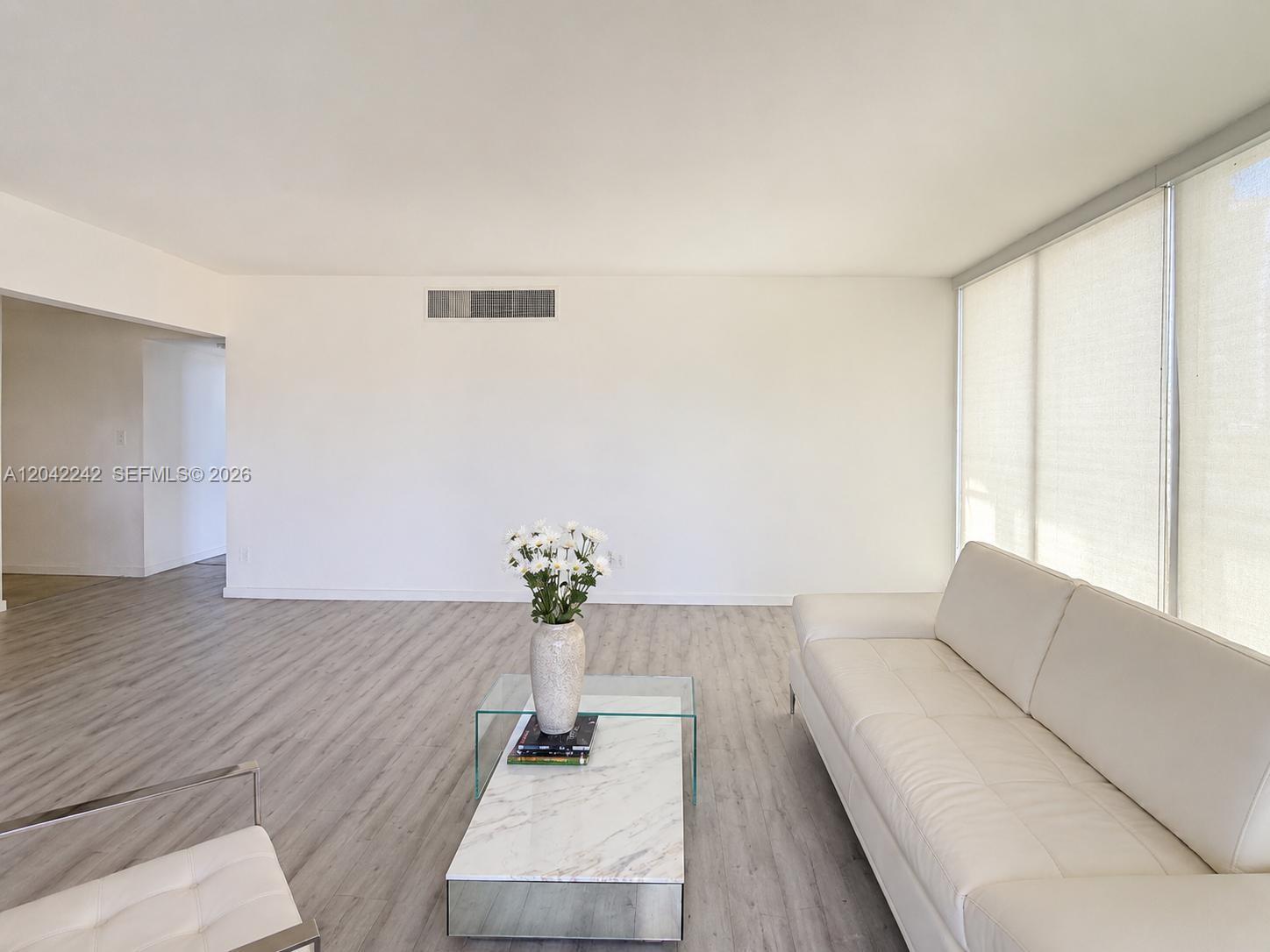 A bright living room features light wood-look flooring, a white sofa, and a marble coffee table — 10275 Collins Ave # 431, Bal Harbour FL 33154, BAL HARBOUR, FL