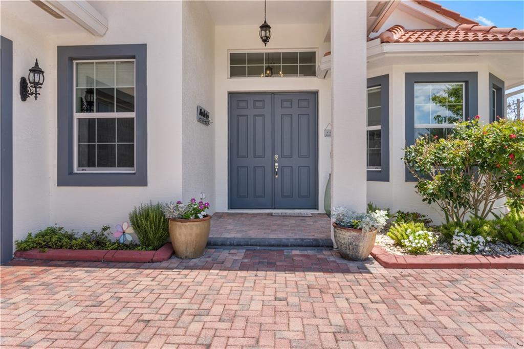 A front entrance features a double door, brick paver walkway, and potted plants — SEBASTIAN, FL