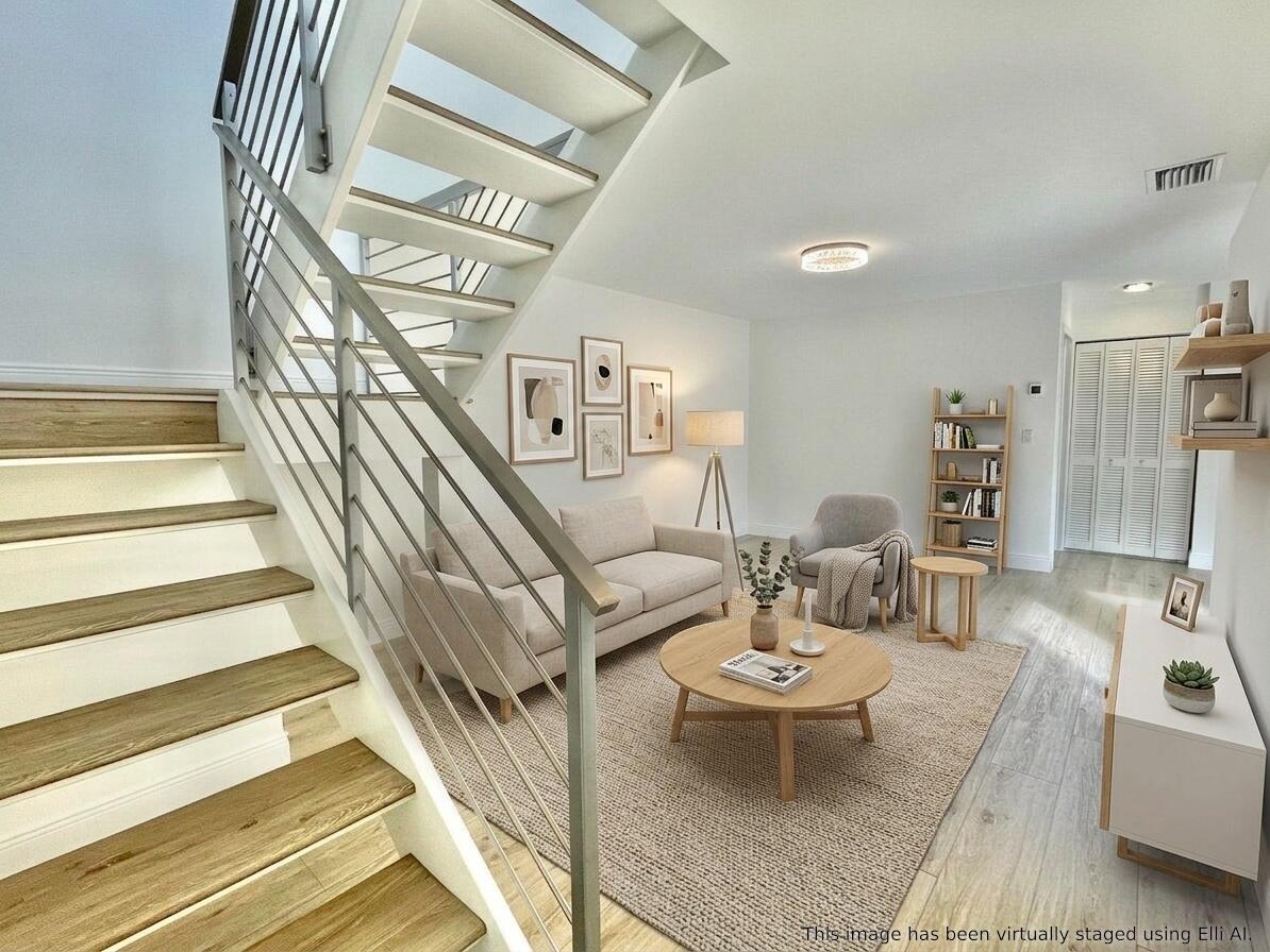 This is a virtually staged living room featuring a staircase with wood treads and metal railings — 359 Prestwick Circle # 2, Palm Beach Gardens FL 33418, PALM BEACH GARDENS, FL