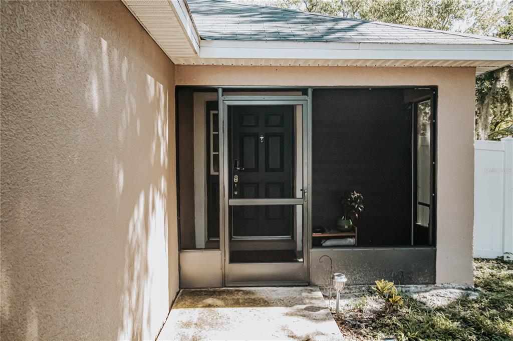 A covered entryway features a screen door leading to a dark front door — 307 NW 8TH STREET, MULBERRY, FL