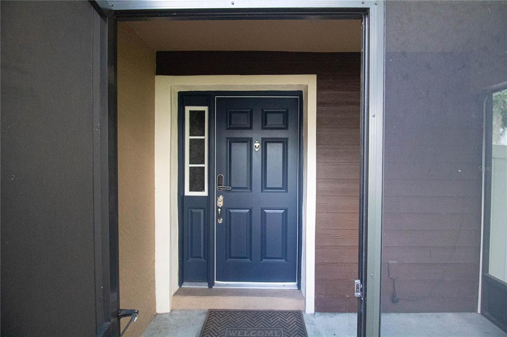 A dark blue front door with a side window is framed by a screen door — 307 NW 8TH STREET, MULBERRY, FL